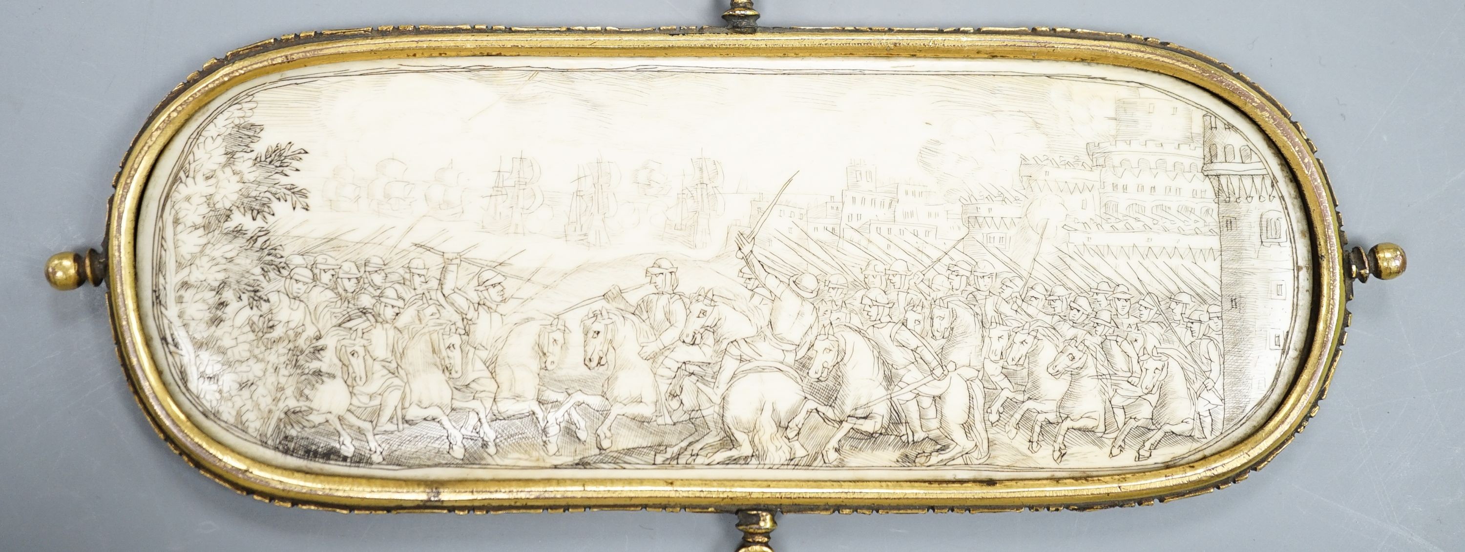 A 17th century French oval ivory plaque in a revolving metal surround, etched on both sides with battle scenes and ships in the background 17cm